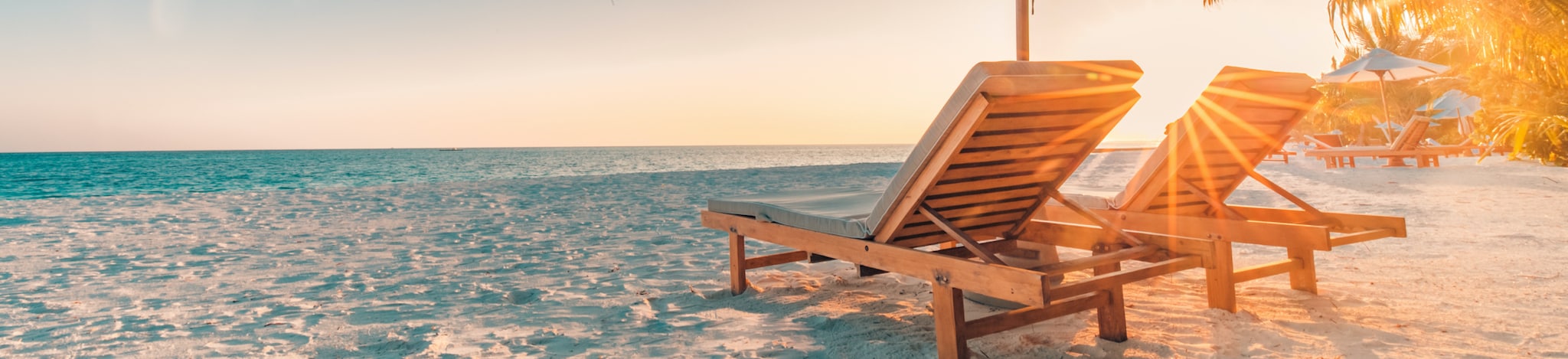 Liegestühle mit Sonnenschirm am Strand